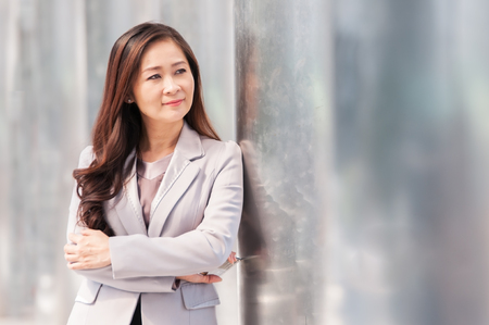 Asian middle business woman leaning stainless steel pole.の写真素材