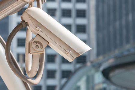 Modern cream CCTV video recorder hanging on roof with blur building background.  Security camera...