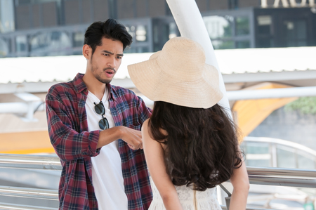 Man wearing long sleeve shirt be angry woman that wearing white dress with big summer hatの写真素材
