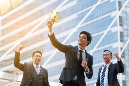 Success business man holding golden trophy cup with right hand, Business executives rejoice in their leadership in business competition.  Congratulations to the gold trophy.の写真素材
