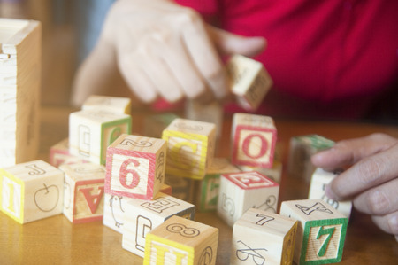 Unidentified people in red cloth playing character letters wooden block on table, relaxing concentrate brain training.のeditorial素材
