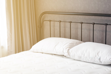 Clean vintage bed black flame white mattress 2 pillows and curtain with sun light in morning in bedroom loft style, loft interior conception.の写真素材