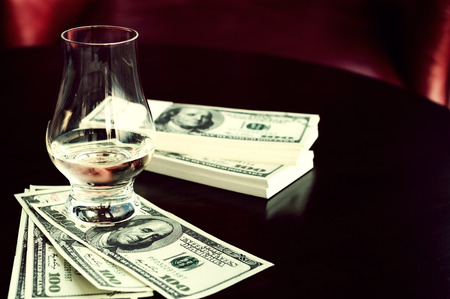 Exclusive Scott and Japanese whisky with dollars bank notes on wooden table in luxury bar, tip for good service.  Film tones conception.の写真素材