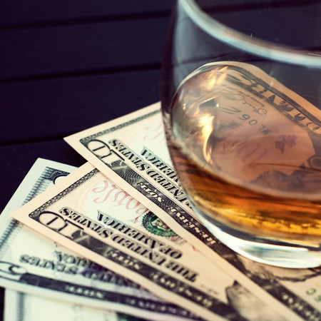 Exclusive Scott and Japanese whisky with dollars bank notes on wooden table in luxury bar, tip for good service.  Film tones conception.の写真素材