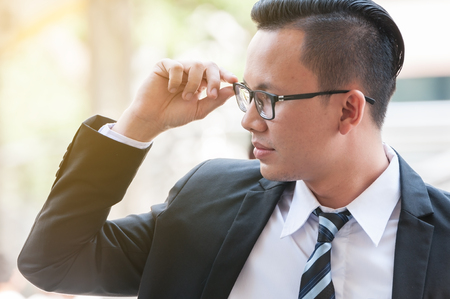 Young Asian business manager touch on his glasses to make some marketing strategy idea for planning solution his business and customer.の写真素材
