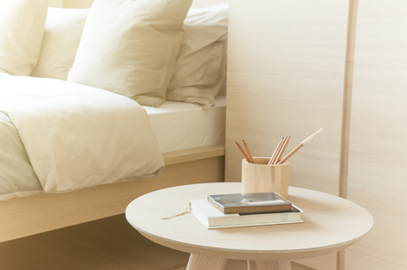 Bedroom with pillow closet and small wooden table with books pencils on table in nature warm tone in...