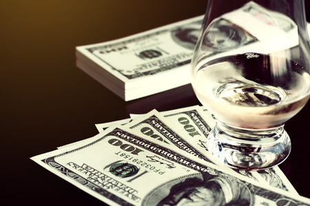 Exclusive Scott and Japanese whisky with dollars bank notes on wooden table in luxury bar, tip for good service.  Film tones conception.の写真素材