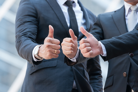 Unidentified business people show victory  sign by thumb up, body language to completed project.の写真素材