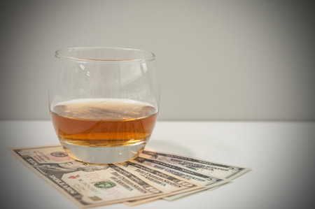 Exclusive Scott and Japanese whisky with dollars bank notes on wooden table in luxury bar, tip for good service.  Film tones conception.の写真素材