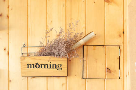 Plank wooden wall with morning box hanging contain dry flower and roll newspaper with space.の写真素材