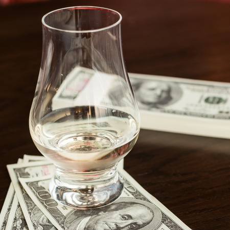 Exclusive Scott and Japanese whisky with dollars bank notes on wooden table in luxury bar, tip for good service.  Film tones conception.の写真素材