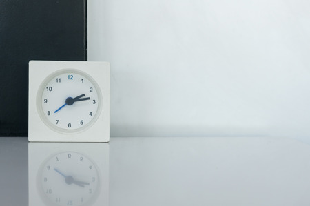 square white alarm clock on marble table and black and white background.