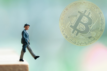 Selective focus miniature business people wearing hat looking to cloudy golden bitcoin investment, unaware with the exchange rate risk,  no investment information make people in risk.の写真素材