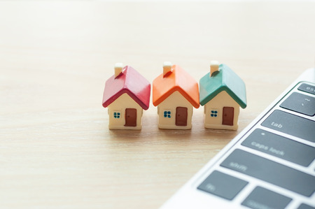 Miniature houses mortgage next to modern laptop with copy space, Real estate online investment and business house loaning marketing on internet.の写真素材