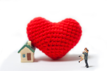 Selective focus miniature couple love just married with big love and new house, saving for new family house.  Red wool heart and jumping hug.の写真素材