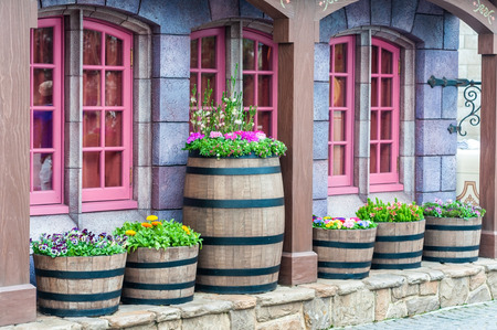 Vintage and antique building with pink frame windows decoration by cask barrel and various flowers.  House gardening with antique flower pot.の写真素材