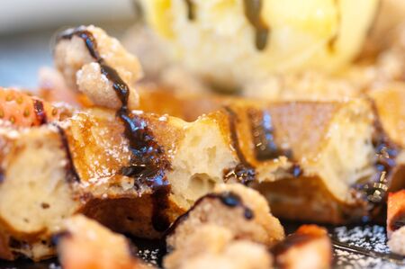 Vanilla ice-cream with hot waffle and pieces of fresh strawberry and chocolate sauce.