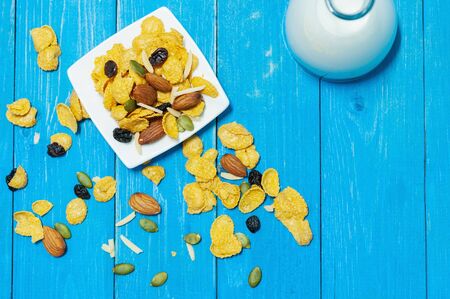 Cornflakes mix with almond rasin sunflower seeds on blue wooden plank.  Breakfast for children healthty food.の写真素材