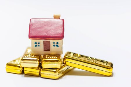 Selective focus miniature home red roof with stack of golden bars, saving and invest for new residence.  Real estate business investment with gold.の写真素材