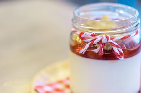 Strawberry Panna Cotta in glass can lay on circle wooden tray with stainless spoon and red cross napkin.の写真素材