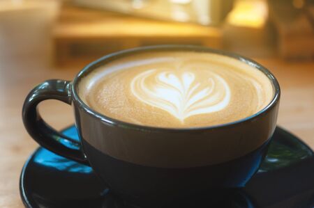 Latte art coffee in black cup set on wooden table, beverage art by fresh milk with coffee.の写真素材