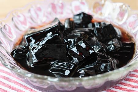 Glass jelly serve in crystal glass bowl on red strip napkin.  Glass jelly is a popular dessert in...