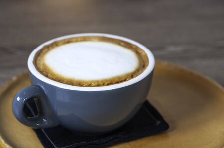 Hot cappuccino coffee with white cream foam serve in coffee cup set, lay on wooden round tray, classice coffee drink.の写真素材