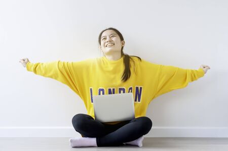 New normal life, Asian female teenager use 18 years old do online learning from home by laptop, woman wearing casual yellow cloth use laptop for work from home during corona virus crisis. Thailand.の写真素材
