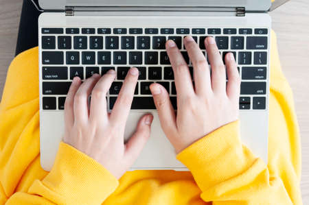 New normal life, Asian female teenager use 18 years old do online learning from home by laptop, woman wearing casual yellow cloth use laptop for work from home during corona virus crisis. Thailand.の写真素材