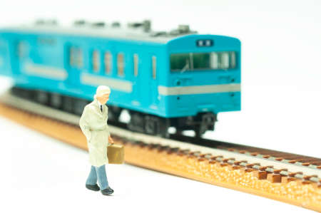 Businessman with cover cloth and brief case walking next to train, selective focus miniature travel by vintage train.  Transportation business concept.の写真素材