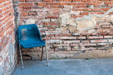 Blue plastic chair in conner of red brick wall, vintage brick wall with old chair.の写真素材