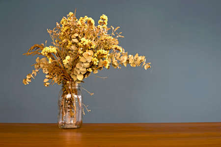 Dry flowers in glass vase on the wood table and plane backgroundの写真素材