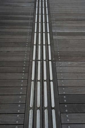 Metal braille block on wood floor.の写真素材
