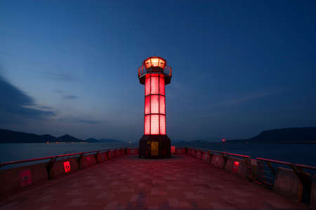Red lighthouse on dark blue sky.