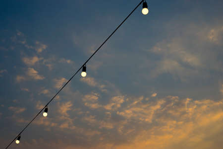 Light bulb on the line and cloudy blue sky on background.の写真素材