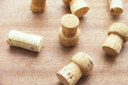 Seven caps of cork champagne randomly scattered on a wooden board.