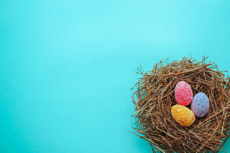 Easter ornamental eggs in a nest on a blue background. See from above. Easter card with space for...