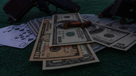 Playing poker or blackjack for money. On the green table are a pistol with cartridges, cash dollars...