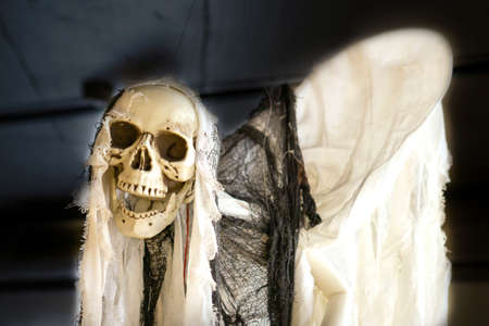 Skeleton disguised as a ghost on a black background, close-up. Halloween concept. High quality photo