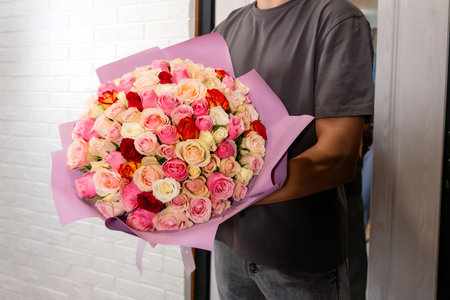 delivery man delivers a bouquet of beautiful flowers to homeの写真素材