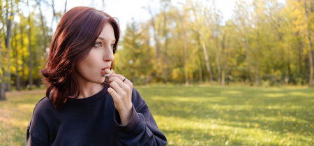young girl with a pensive look enjoys a cold treat, her gestures harmonize with the fall landscape...