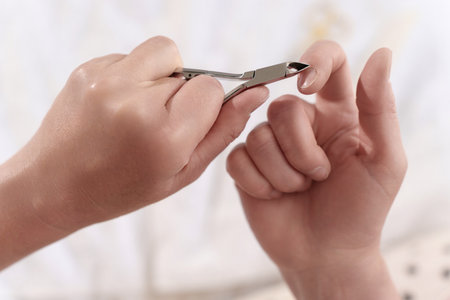 Close-up of womans hands carefully trimming cuticles with clippers, achieving healthy and lovely nailsの写真素材