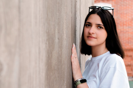 Teenager girl leaning against concrete wall wearing sunglasses and smartwatchの写真素材