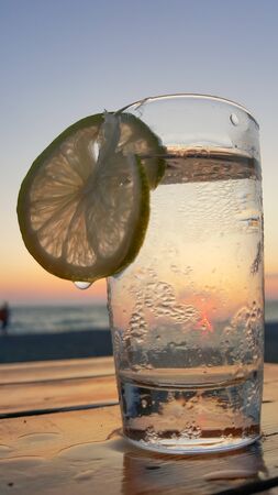 A glass of gin and tonic with lime at sunset. Glass close-up.の写真素材