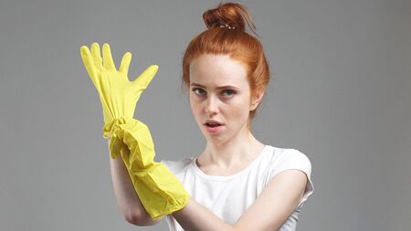 Beautiful girl wearing yellow rubber cleaning gloves smiles widely. isolated on grey background.の写真素材