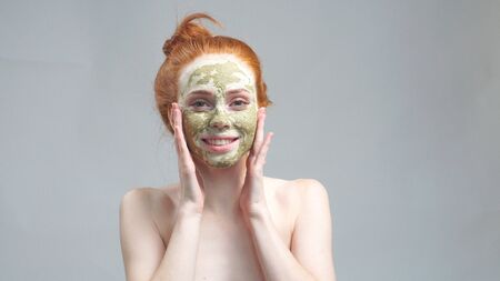 Skin care. A young woman with a green-and-white mud mask on her face.の写真素材