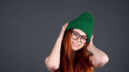 Positive dreamy red-haired woman looking at the camera, isolated grey background.の写真素材