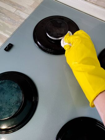 Hand in protective gloves cleans the gas stove with a rag.の写真素材