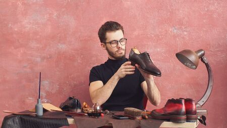 talented designer holds boots and checks his work, job, profession.の写真素材
