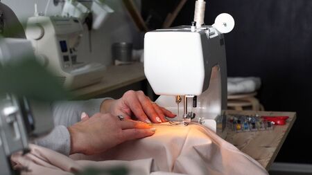 professional seamstress works in her workshop and sews a stylish outfit.